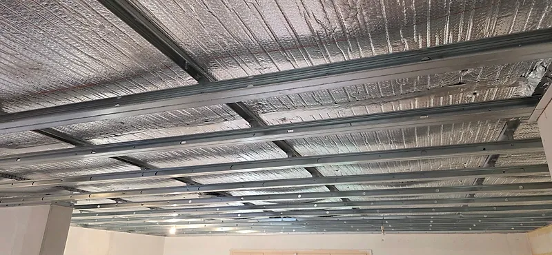 Isolant mince réfléchissant posé au-dessus d'une ossature métallique de plafond en plaques de plâtre